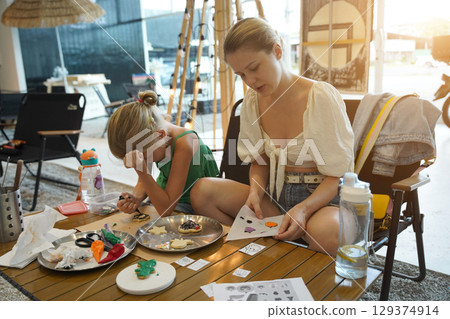 Mother and her daughter paint Halloween cookies  129374914