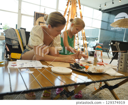 Mother and her daughter paint Halloween cookies  129374919