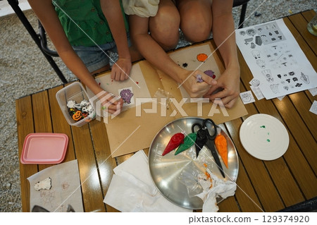 Mother and her daughter paint Halloween cookies  129374920