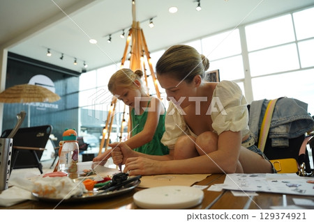 Mother and her daughter paint Halloween cookies  129374921