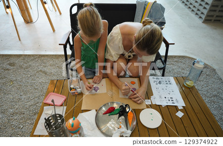 Mother and her daughter paint Halloween cookies  129374922