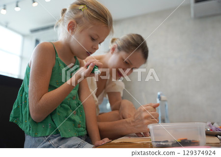 Mother and her daughter paint Halloween cookies  129374924