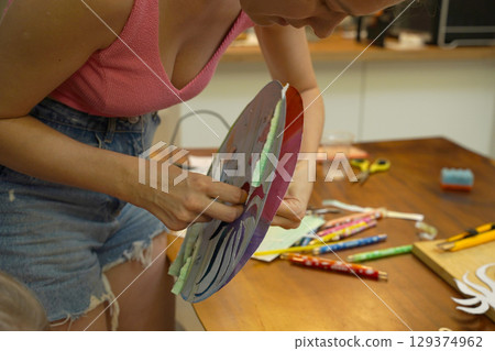 A mother and her young daughter engage in a colorful painting activity  129374962