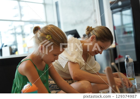 Mother and her daughter paint Halloween cookies Mother and her daughter paint Halloween cookies 129374987