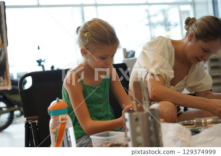 Mother and her daughter paint Halloween cookies  129374999