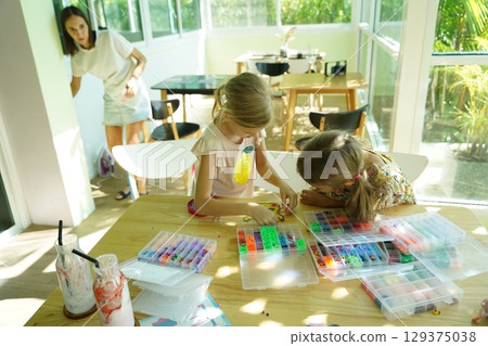 Teacher in workshop teched two girls how to assemble a thermo mosaic Teacher in workshop teched two girls how to assemble a thermo mosaic 129375038