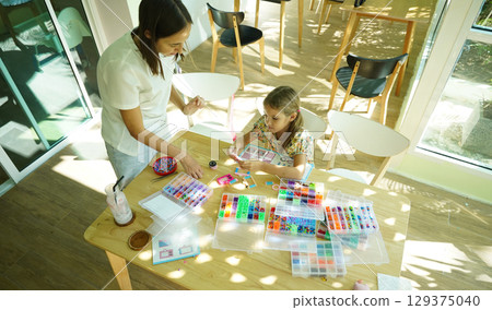 Teacher in workshop teched two girls how to assemble a thermo mosaic Teacher in workshop teched two girls how to assemble a thermo mosaic 129375040