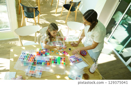 Teacher in workshop teched two girls how to assemble a thermo mosaic Teacher in workshop teched two girls how to assemble a thermo mosaic 129375041