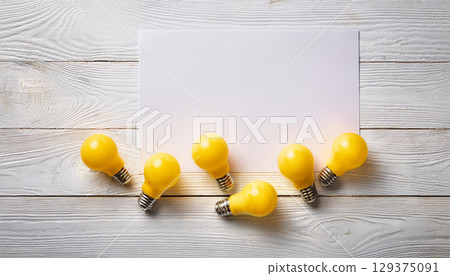 Bright Yellow Light Bulbs and Blank White Paper on Rustic Wooden Background for Creative Ideas 129375091
