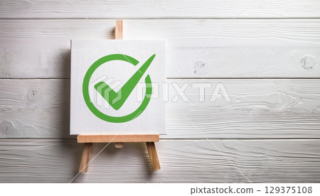 Green Check Mark Symbol on Canvas with Wooden Easel Against White Rustic Background Approval Concept 129375108
