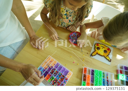Teacher in workshop teched two girls how to assemble a thermo mosaic Teacher in workshop teched two girls how to assemble a thermo mosaic 129375131