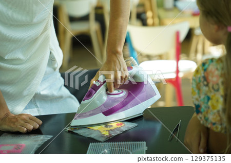 Teacher in workshop teched two girls how to assemble a thermo mosaic  129375135
