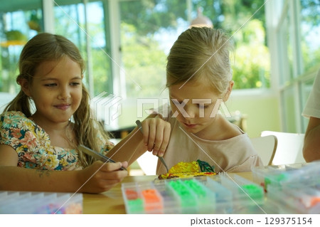 Teacher in workshop teched two girls how to assemble a thermo mosaic  129375154