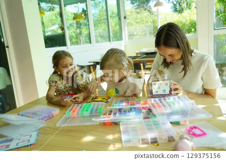 Teacher in workshop teched two girls how to assemble a thermo mosaic  129375156