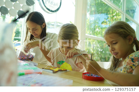 Teacher in workshop teched two girls how to assemble a thermo mosaic  129375157