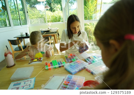 Teacher in workshop teched two girls how to assemble a thermo mosaic  129375189