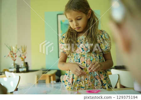 Teacher in workshop teched two girls how to assemble a thermo mosaic  129375194