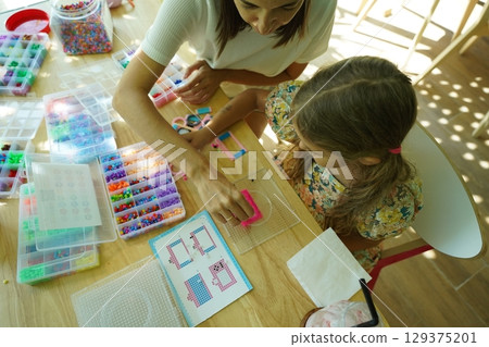 Teacher in workshop teched two girls how to assemble a thermo mosaic  129375201
