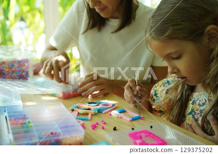Teacher in workshop teched two girls how to assemble a thermo mosaic  129375202