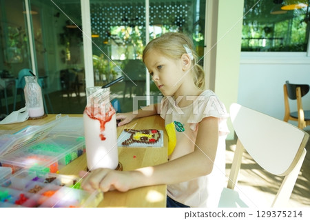 Teacher in workshop teched two girls how to assemble a thermo mosaic  129375214