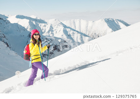 Solo Female Climber Ascends Snowy Mountain Peak Under Clear Winter Skies 129375765