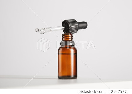 Black cap with pipette lies on open brown glass bottle. Black cap with pipette lies on open brown glass bottle. 129375773