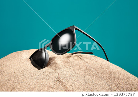 Sunglasses, shades with black frame, lenses in sand. Sunglasses, shades with black frame, lenses in sand. 129375787