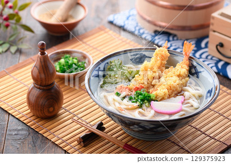 熱氣騰騰的新鮮天婦羅烏龍麵，配上紫蘇葉、炸蝦、星形胡蘿蔔和蔥花。溫暖的日式冬季午餐。 129375923