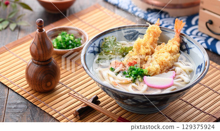 熱氣騰騰的新鮮天婦羅烏龍麵，配上紫蘇葉、炸蝦、星形胡蘿蔔和蔥花。溫暖的日式冬季午餐。 129375924