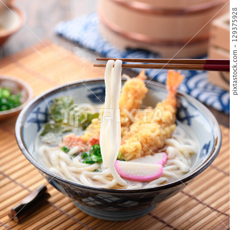 熱氣騰騰的新鮮天婦羅烏龍麵，配上紫蘇葉、炸蝦、星形胡蘿蔔和蔥花。溫暖的日式冬季午餐。 129375928