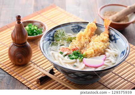 熱氣騰騰的新鮮天婦羅烏龍麵,配上紫蘇葉、炸蝦、星形胡蘿蔔和蔥花。溫暖的日式冬季午餐。 熱氣騰騰的新鮮天婦羅烏龍麵,配上紫蘇葉、炸蝦、星形胡蘿蔔和蔥花。溫暖的日式冬季午餐。 129375939