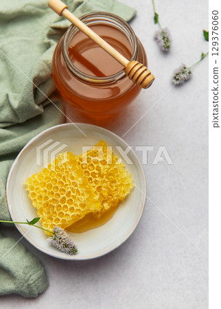 Honeycomb and honey jar with wooden dipper on kitchen table 129376060
