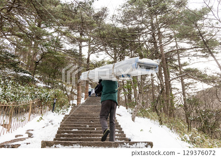 Porter workers carrying construction materials along steep steps at Huangshan or Yellow Mountain. Porter workers carrying construction materials along steep steps at Huangshan or Yellow Mountain. 129376072
