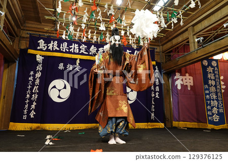 石見神樂(夜神樂)表演者在神社的祭祀殿舞台上跳舞 石見神樂(夜神樂)表演者在神社的祭祀殿舞台上跳舞 129376125