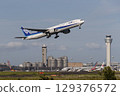 A plane taking off with the control tower in the background 129376572