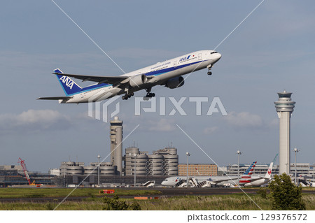 A plane taking off with the control tower in the background 129376572
