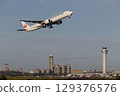 A plane taking off with the control tower in the background 129376576