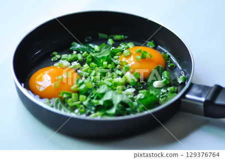 fried egg or sunny side up egg with vegetable topping before fry 129376764