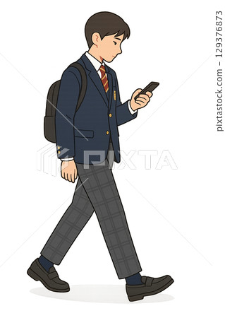 A high school boy walking home while looking at his smartphone 129376873