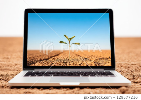 Minimal desk setup with laptop displaying plant growth on a barren landscape Minimal desk setup with laptop displaying plant growth on a barren landscape 129377216