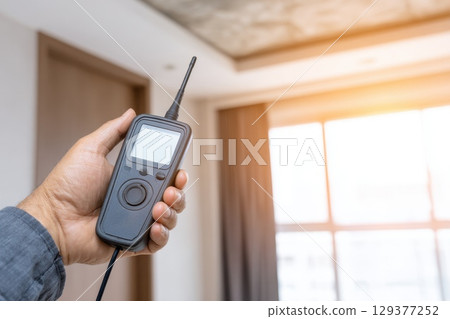 Close Up of Inspector's Hand Holding Moisture Measurement Device in Bright Interior Setting Close Up of Inspector's Hand Holding Moisture Measurement Device in Bright Interior Setting 129377252