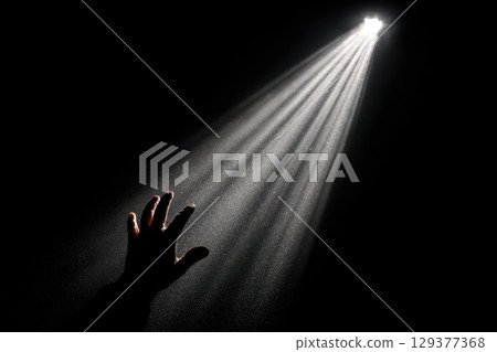 A Hand Reaching Toward a Distant Light in the Darkness Symbolizing Hope and Spiritual Connection A Hand Reaching Toward a Distant Light in the Darkness Symbolizing Hope and Spiritual Connection 129377368