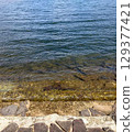 Crystal clear lake water and stone pavement on the shore 129377421