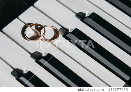 two wedding rings resting on piano keys create beautiful symbol love and music in harmonious setting 129377433