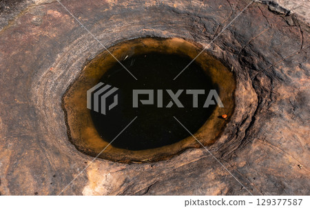 The holy well on Naga Cave, located in the Bueng Kan province of Northeastern Thailand. This strange and amazing beauty of the hole stone shaped like a giant snake eye. 129377587
