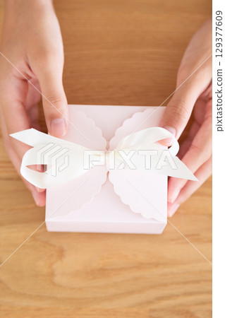 Hands of a middle school girl holding a present Hands of a middle school girl holding a present 129377609