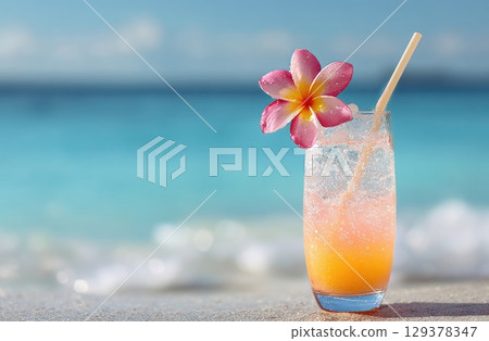 hand holding a tropical cocktail with a straw and a pink plumeria flower on a beach hand holding a tropical cocktail with a straw and a pink plumeria flower on a beach 129378347