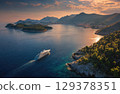 A luxury yacht sailing between islands in the sea drone shot. 129378351