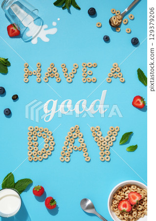 Words Have a good day made of cereal rings, milk, strawberries, blueberries and mint leaves on a blue background. Positive breakfast idea. Words Have a good day made of cereal rings, milk, strawberries, blueberries and mint leaves on a blue background. Positive breakfast idea. 129379206