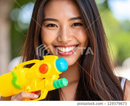 Young woman playing with a water gun 129379673